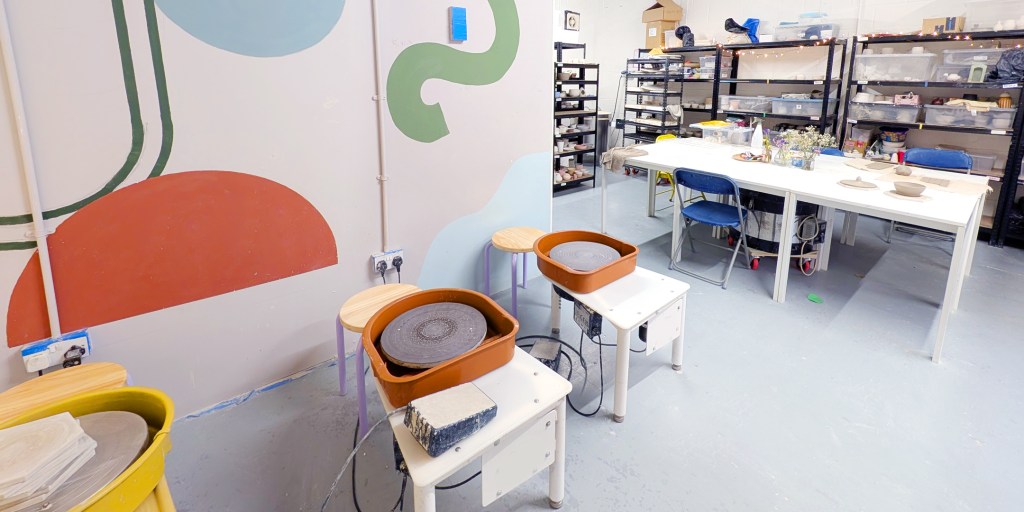 wide view of pottery studio that has three wheels and some desks